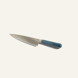 A stainless steel chefs knife with a blue handle is placed on a plain white background.
