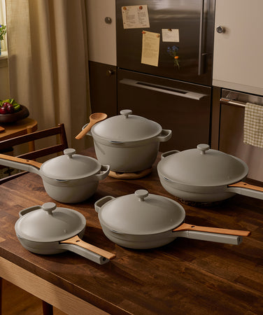 Set of gray cookware on a wooden table in a kitchen.