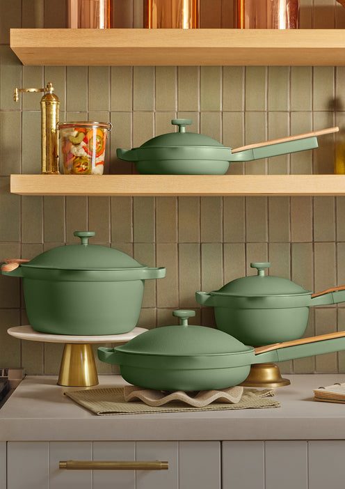 Green cookware set on a kitchen counter with copper accents