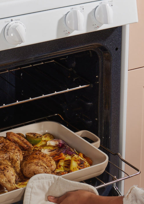 beige griddle pan with chicken and roasted vegetables in oven