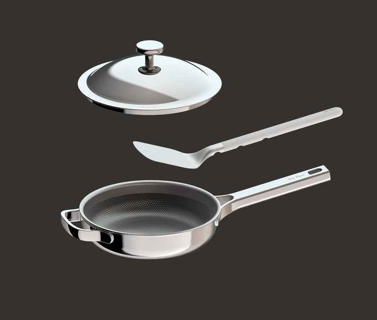 A stainless steel frying pan with a long handle, a matching metal lid, and a spatula are displayed on a dark background, arranged so each item appears to be floating above the other.
