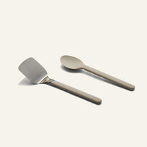 Titanium Pro Utensil Set including a metal spatula with a light-colored handle and a matching light-colored solid spoon.