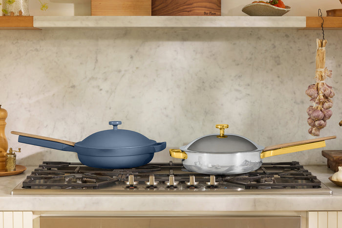 A blue pan and a chrome and gold pan on a stovetop
