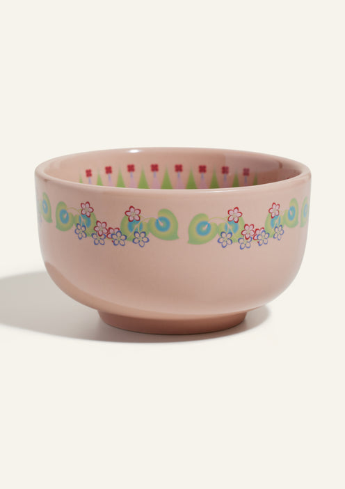 A pink ceramic bowl with a decorative pattern of green swirls and small red and blue flowers around the exterior.