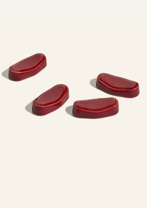 Four red, oval-shaped gummy supplements are arranged on a plain light background.
