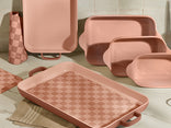 Set of pink ceramic trays and containers on a tiled floor.