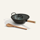 Black wok with wooden handle and spatula on a white background