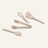 Four beige Mini Utensil Essentials—spatula, tongs, slotted turner, and whisk—are arranged on a plain light background.