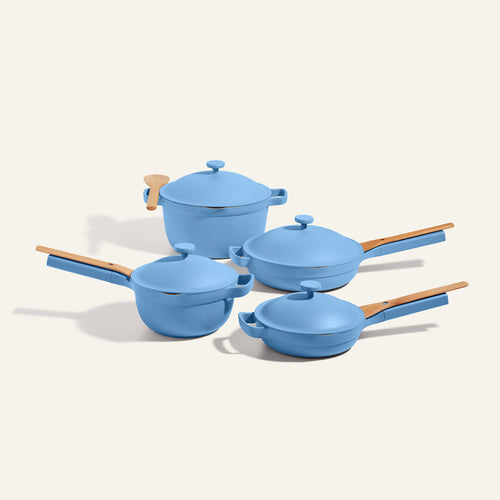 Set of blue cookware with wooden handles on a light background
