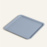 A square, light blue tray with slightly raised edges, placed on a light beige background.