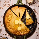 green cast iron always pan with corn bread on tablecloth