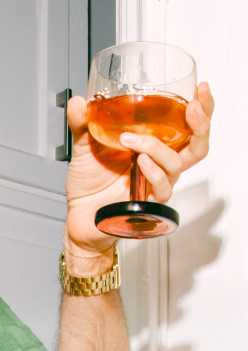 Raising a Party Coupe with an orange drink in the air