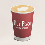 Red coffee cup with 'Our Place Los Angeles' text on a beige background