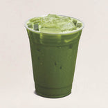 Green iced drink in a clear plastic cup on a light beige background