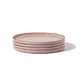 A stack of four pink ceramic plates with a simple, modern design, placed on a plain white background.