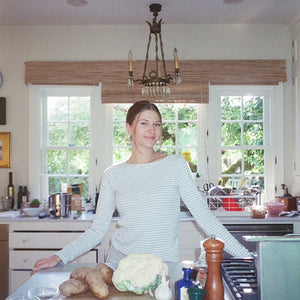 Woman standing in a kitchen with a chandelier above