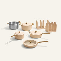 Set of beige cookware including pots, pans, and a strainer on a white background