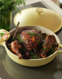Roasted chicken in a yellow ceramic pan on a kitchen counter
