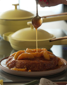 Pancake being drizzled with syrup on a plate with a blurred background