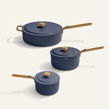 Set of three blue cookware pots with gold handles on a white background