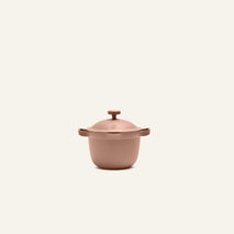The Petite Perfect Pot, a matte light brown cooking pot with two side handles and a lid, is centered on a plain off-white background.