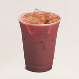 Red smoothie with ice cubes in a clear plastic cup on a light beige background