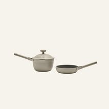 The Tiny Cookware Duo, featuring a gray saucepan with lid and a matching frying pan, both with long handles, is displayed on a plain light background.